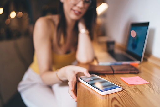 Selective focus on modern smartphone device used by unrecognizable female freelancer checking received text email or app notification, skilled woman browsing website on digital cellular technology